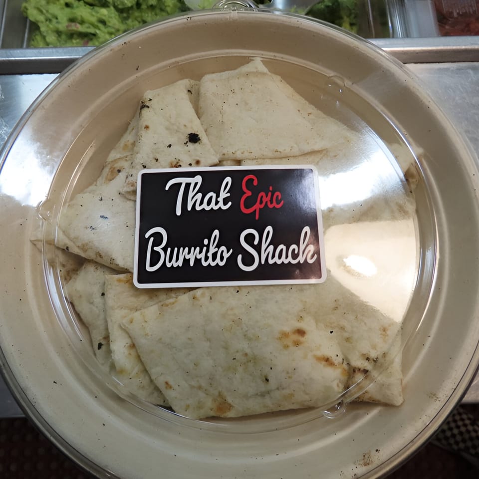 Folded tortillas in a plastic container with a "That Epic Burrito Shack" label.