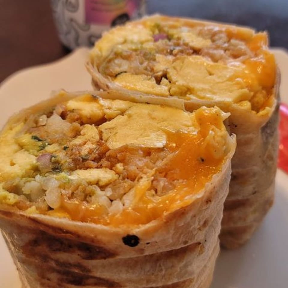 Two That Epic Burrito Shack burritos, cut in half, revealing a savory filling of eggs, cheese, and rice.
